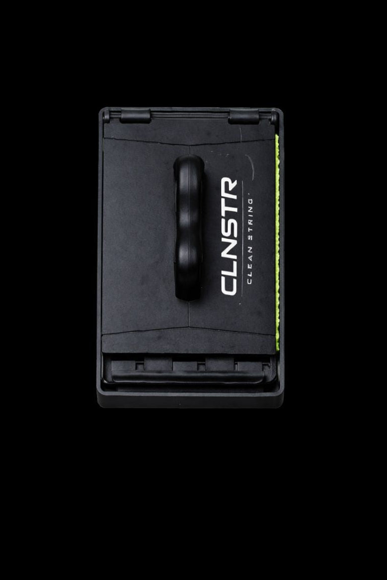 CLNSTR guitar string cleaner shown vertically on a black background, featuring a black ergonomic handle with green microfiber cleaning pad