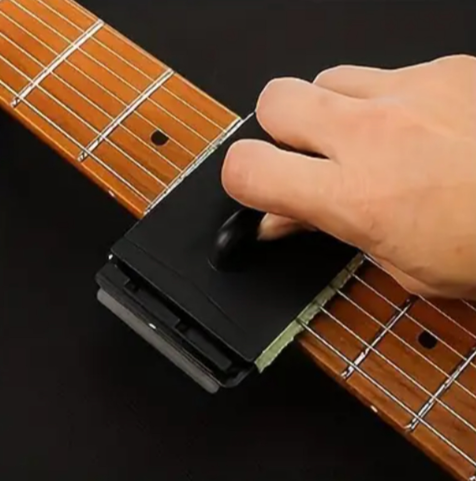 Guitar string cleaner sliding along the fretboard to remove grime and oils