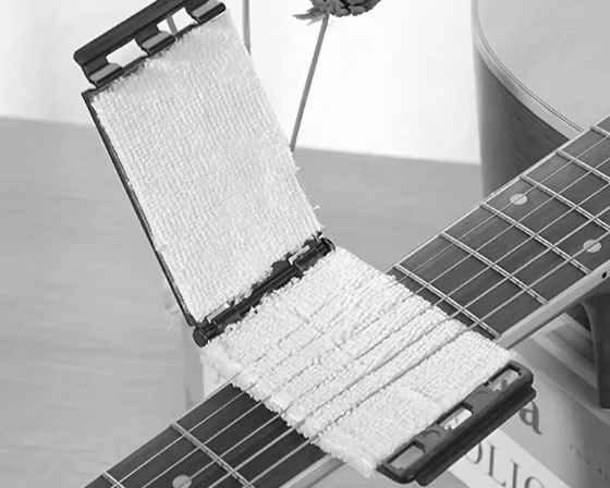 Guitar string cleaning tool clamped onto strings for deep cleaning