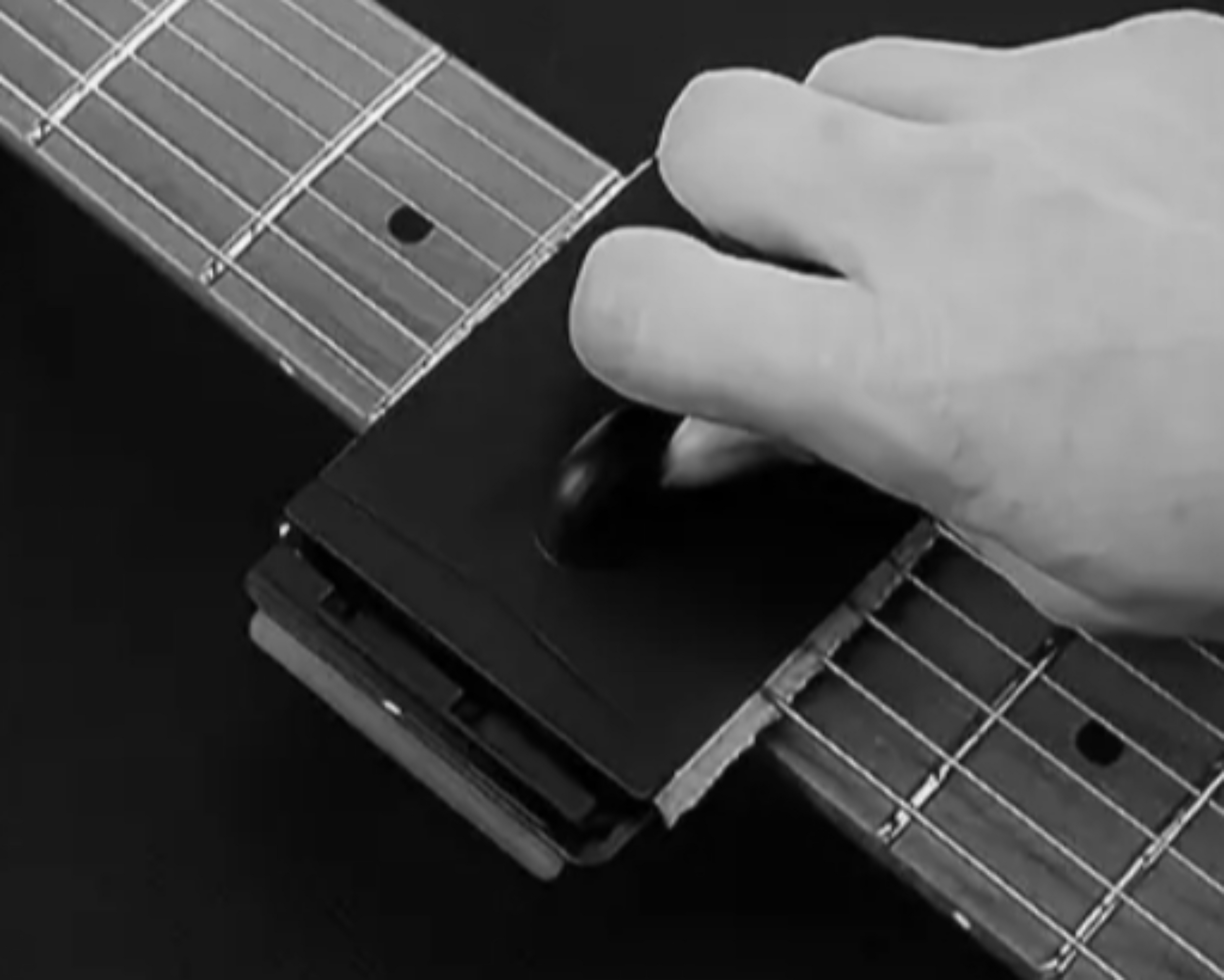 Guitar string cleaner sliding along fretboard to remove grime and oils